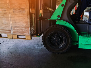 Worker driving forklift loading shipment carton boxes goods on wooden pallet at loading dock from container truck to warehouse cargo storage in freight logistics, transportation industrial, delivery
