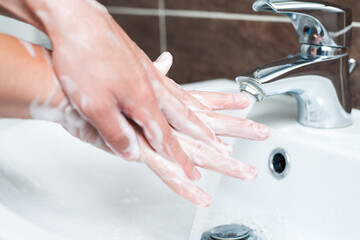 Hygiene concept. Washing hands with soap under the faucet with water