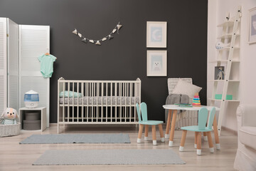 Cute baby room interior with modern crib near dark wall