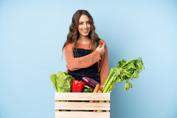 Farmer with freshly picked vegetables in a box pointing back