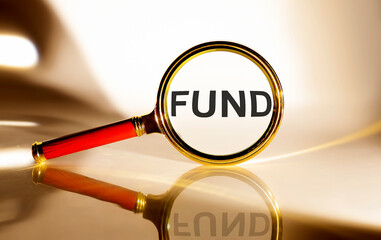 FUND concept. Magnifier glass with text on white background in sunlight.