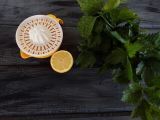 yellow juicer next to half a lemon and a bunch of celery