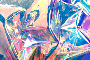 Colorful glittering holographic background. Defocused wrinkled foil reflections with little bokeh.
