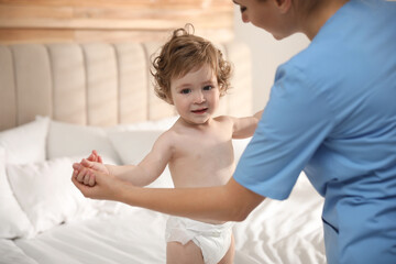 Obraz na płótnie Canvas Orthopedist examining cute little baby on bed
