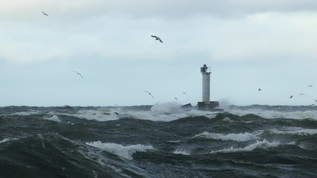 Port entry lighthouse on breakwater as seen over stormy sea