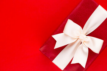 Christmas gift boxes with ribbons on red tabletop.