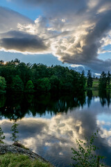 Beautiful cloudy sky has reflection in forest lake during sunset