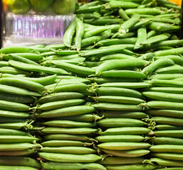 green fava beans in pods on counter in market