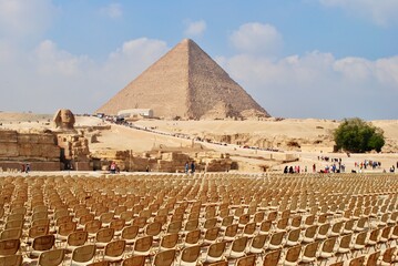 Fototapeta na wymiar Row of empty seats for light show in front of the pyramids and the Sphinx on a sunny day. UNESCO World Heritage site. Giza Egypt