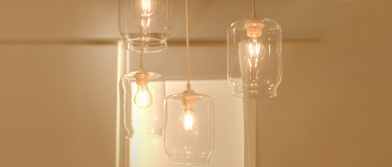 Four glass electric lamps burn in a bright room on a light warm background. Concept loft style, underground style