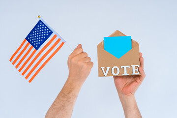 Hand of American voter. Resident of USA posting ballot or vote inside postal envelope. America flag...