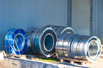 Steel. Metal. Large steel coils are standing at wall. Galvanized steel rolls lie on ground. Metal...