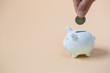 Close up female hand putting coin into piggy bank, save money for future