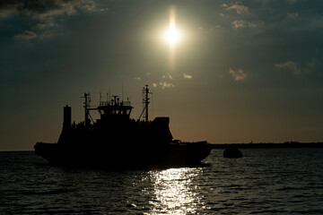 Fototapeta premium Transportation ferry at sea in the rays of the evening sun.