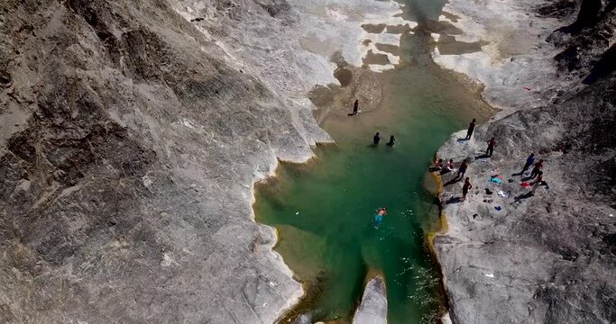 Kid boys are playing happy in the nature, joyful swimming in a beautiful clear green river of white water located in a stunning mountain valley in south Iran nature Baluchistan in a sunny pleasant day