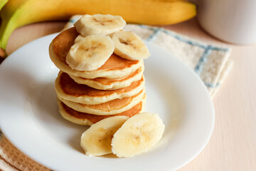 Banana pancakes served with banana on plate