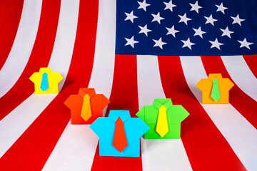 Colorful origami business suits on the background of the American flag. Election race in the United States. American politicians on the background of the flag of the United States of America.