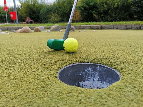 Golfschl&auml;ger mit Ball beim Einlochen