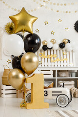 Birthday decorations - gifts, toys, balloons, garland and figure for little baby party on a white wall background.