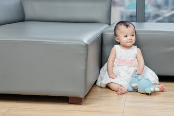 Cute little girl in puffy dress sitting on the floor and playing with toy