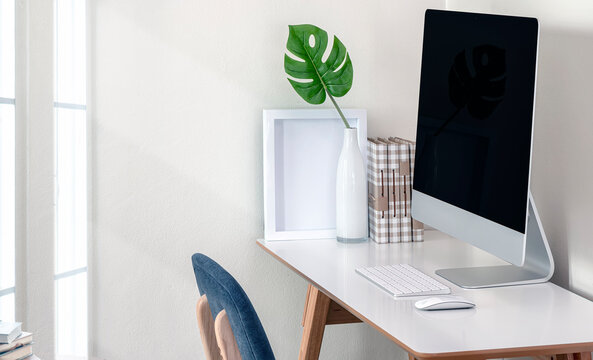 Mockup monitor with keyboard, mouse and houseplant on the table in white room.