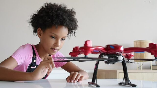 Young cute girl exploring quadcopter. Child playing with drone at home. Education, home studying, children lifestyle, technology, science, future and people concept