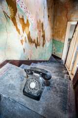 Old vintage telephone on stairway of old decaying abandoned building