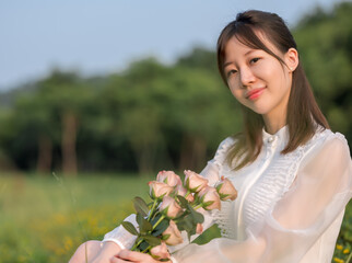 A woman hold flowers and sit on grassland.