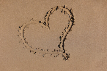 Heart drawn on the sand by sea closeup background. Romantic vacation for newlyweds at sea concept.