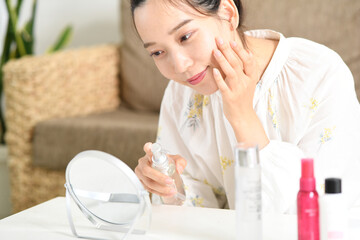 鏡を見ながらスキンケアをする女性