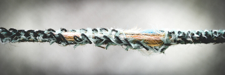 old damaged torn rope closeup view on blurred grey background.