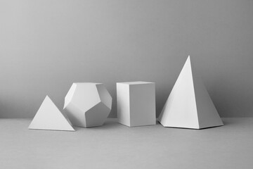 Platonic solids figures geometry. Abstract white color geometrical figures still life composition. Three-dimensional prism pyramid rectangular cube objects on gray background.