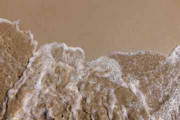 Sea wave washes sandy shore of beach background. Vacation at sea concept.