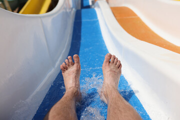 Male feet on background of roller coaster in the water park closeup. Safety rules for water...
