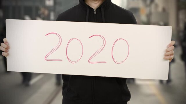 Unknown activist holds a placard with 2020 text