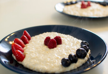 Oatmeal porridge with berries, in a blue plate. Healthy breakfast.