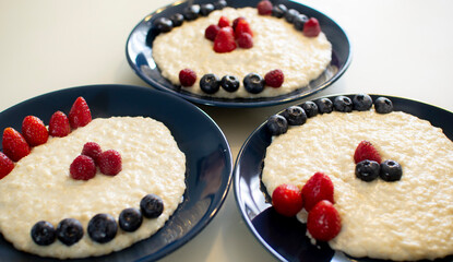 Oatmeal porridge with berries, in a blue plate. Healthy breakfast.