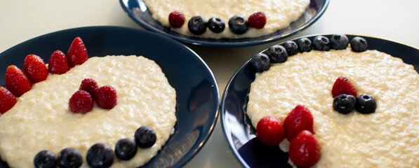 Oatmeal porridge with berries, in a blue plate. Healthy breakfast.