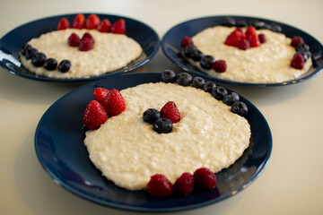 Oatmeal porridge with berries, in a blue plate. Healthy breakfast.