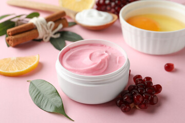 Fototapeta na wymiar Fresh pomegranate and jar of facial mask on pink background. Natural organic cosmetics