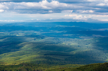 Beautiful view of green hills from above with clouds. Summer landscape from Galyatető Mountain in the Mátra Mountain. 