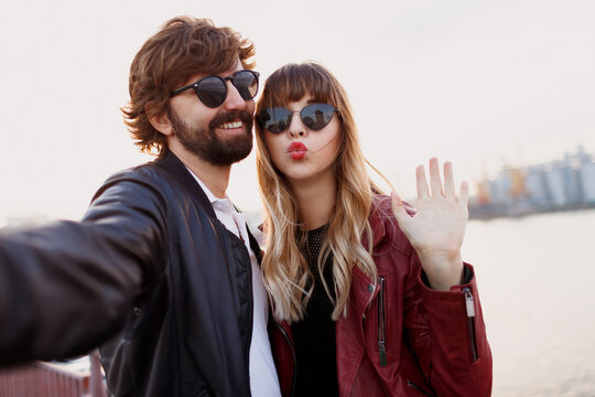 Close up self portrait of cute playful couple having fun and spending romantic moments together . Wearing stylish leather jacket and sunglasses.