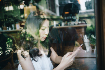 Business asian women use samrtphone sitting in coffee shop