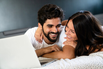 Young couple relaxing at home with laptop. Love, happiness, people and fun concept.