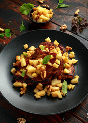 Roasted Pork chops with caramelized apples, walnuts and sage in black plate on wooden table