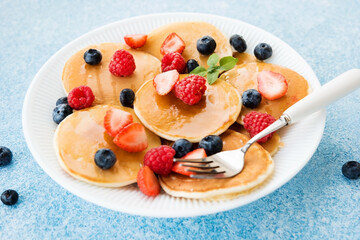 Close-up of American pancakes with honey and berries in a plate