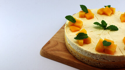 Mango cheesecake decorated with mango pulp and mint leaves