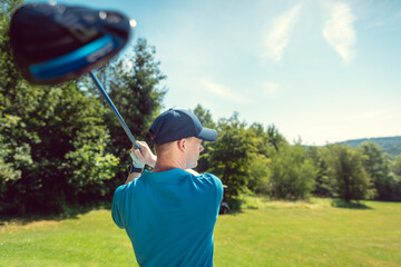 Golf player at the tee on golf course swinging the driver