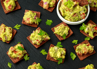Avocado Guacamole with chipotle and poblano whole grain tortilla chips on rustic stone board