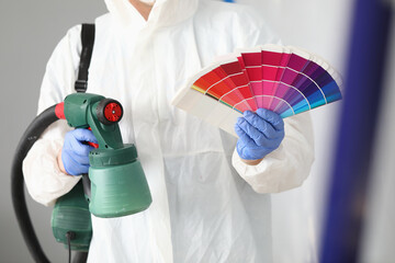 Master holds spray gun and color palette in crayfish. Painting service concept